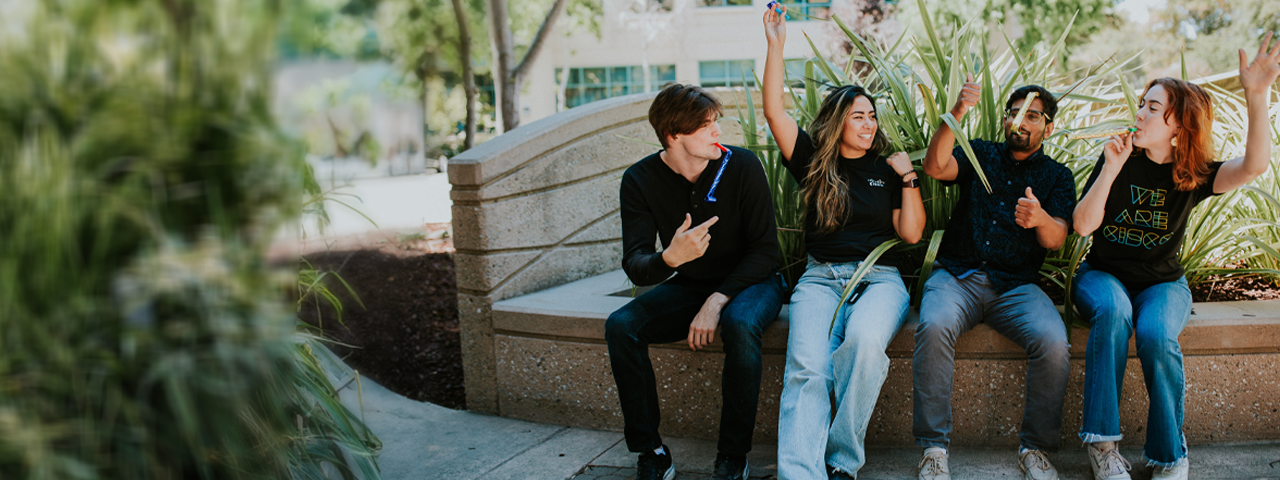 Four people making celebratory gestures.