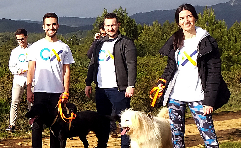 Group of people stand in nature with multiple dogs.