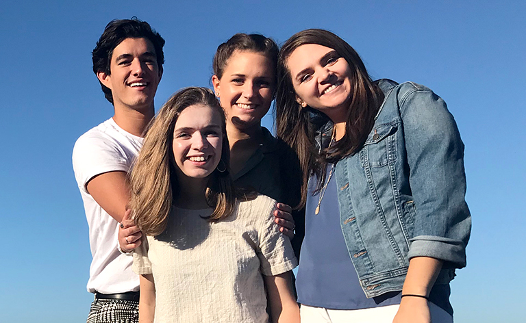 Four people smiling together with the Golden Gate Bridge in the background.