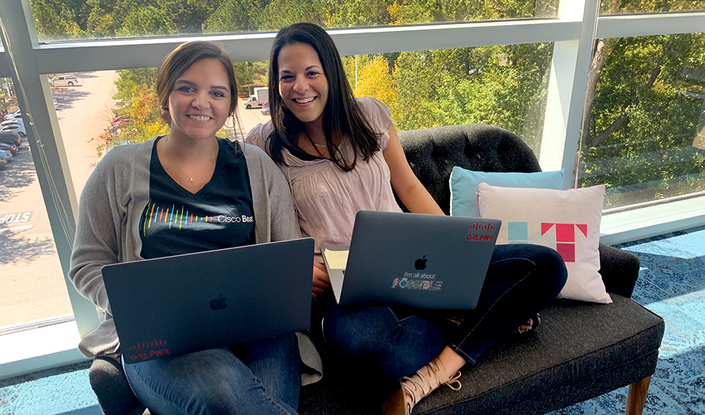 Two people sitting together, each holds a laptop.