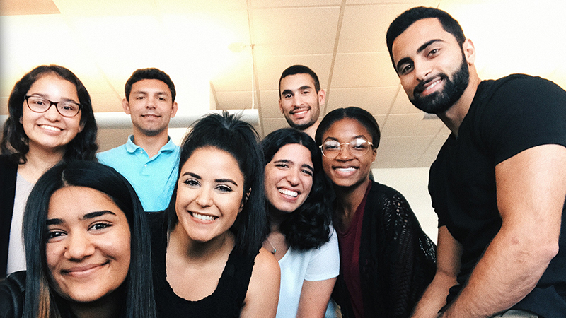 Eight people huddled together and smiling.