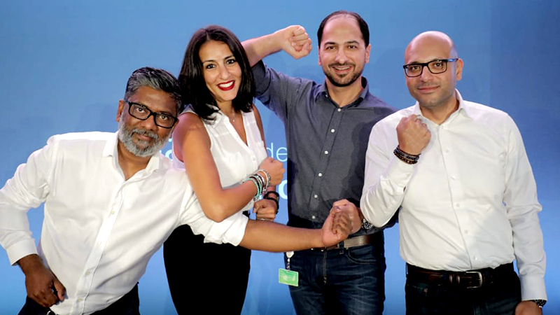 four people huddled together making a fist with one of their hands