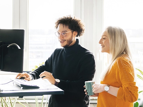 An IT professional at a tall table sharing FSO Platform on their screen with a colleague.