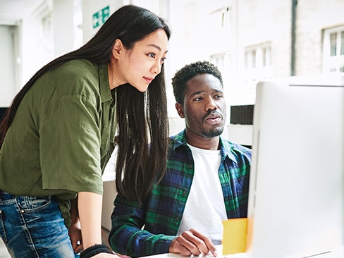 An IT professional at a workstation sharing observability data on their screen with a colleague.